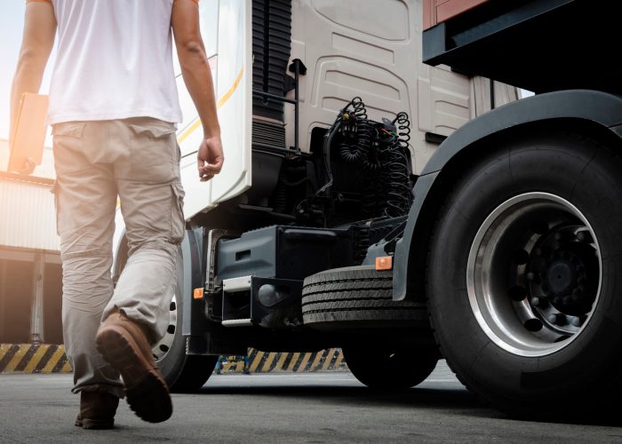 Truck inspection and safety. Truck driver walking around the semi truck daily checking a truck tire.